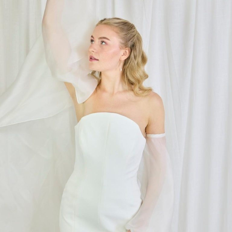 Brautkleid mit Oberteil aus Tüll mit Federn bestickt. Braut trägt cleanes Brautkleid in A-Linie und einem besonderem Federn und Strass.