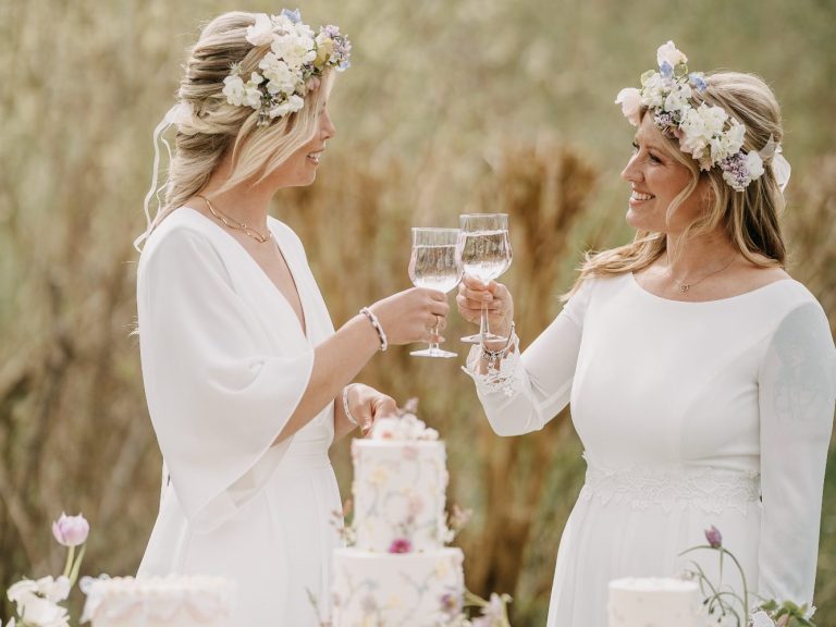 Verschiedene Brautkleidformen und Brautkleidstile. Ob Fit&Flare, Mermaid oder A-Linie - Finde dein Hochzeitskleid bei uns. Ein lesbisches Paar auf ihrer Hochzeit in Kiel beim anstoßen. Tolle Jumper statt Brautkleider und schwedische Blumenkränze.