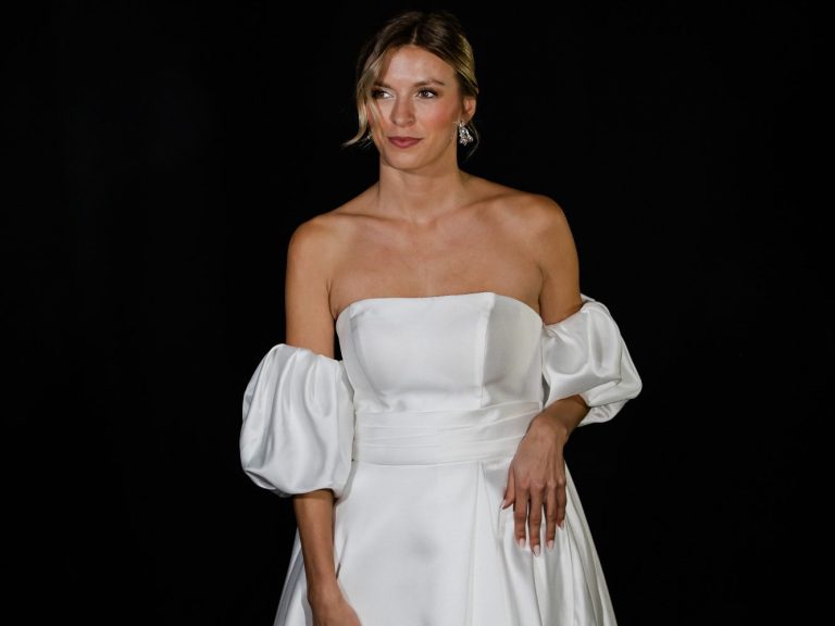 Verschiedene Brautkleidformen und Brautkleidstile. Ob Fit&Flare, Mermaid oder A-Linie - Finde dein Hochzeitskleid bei uns. Trägerloses Brautkleid mit Puffärmeln wird von einer Braut mit strenger Brautfrisur präsentiert.